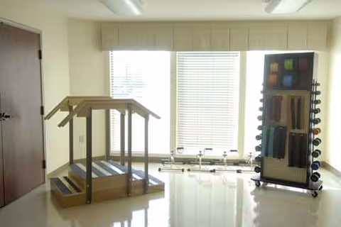 Bright interior exercise room with a wooden step platform and weight rack.