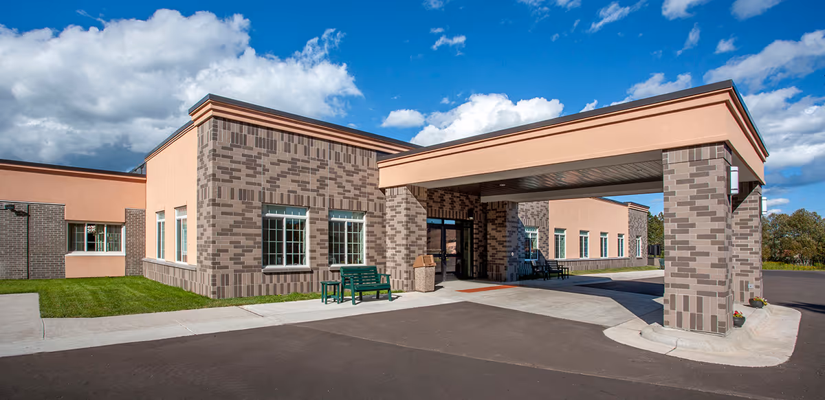 Entrance and porte-cochère of a single-story brick and stucco health center building under a blue sky.