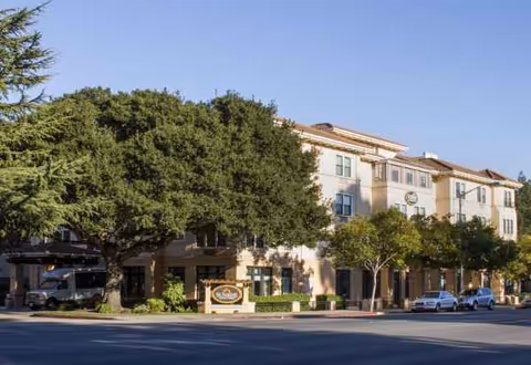Sunrise of San Mateo exterior building with trees, sign, and parked cars
