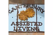 Decorative tile sign that reads 'Canterbury Assisted Living' with yellow autumn leaves.