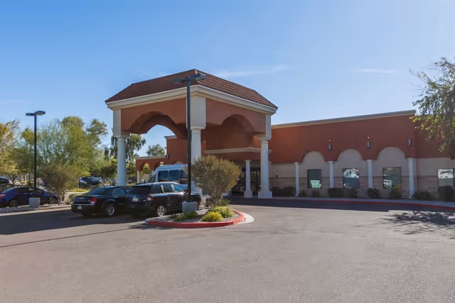 Entrance and porte-cochere of the Mission Palms Post Acute building with parked cars and landscaping in front.