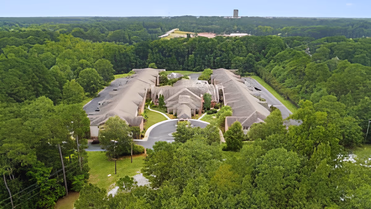 Aerial view of TerraBella Windsor Lake facility surrounded by dense green trees and forested area, showing a large building with multiple wings and a circular driveway at the entrance.