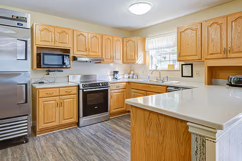 Bright kitchen with oak cabinets, stainless steel appliances, and a white countertop island.