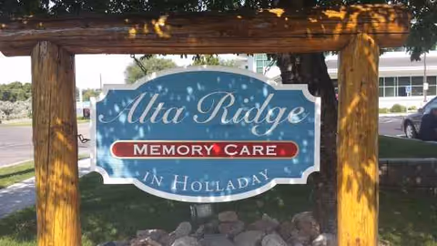 Wooden-framed Alta Ridge Memory Care sign at the outdoor facility entrance.