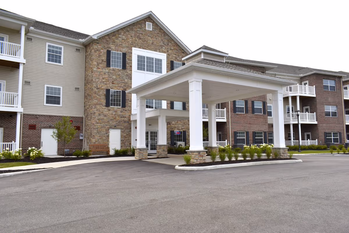 Exterior view of a senior living facility with stone facade and white entrance canopy