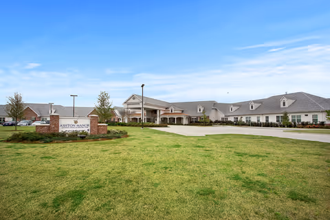 Front exterior of the SummerHouse Ashton Manor senior living facility with a large lawn, driveway, and entrance sign.