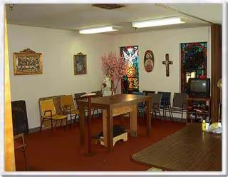 Common room in Evangeline Oaks Guest House with a central high table, chairs, and stained glass.