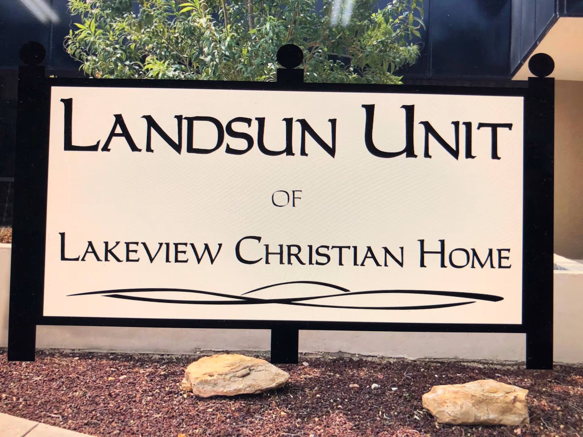 A large outdoor sign reading "Landsun Unit of Lakeview Christian Home" displayed in front of a building with rocks and landscaping.