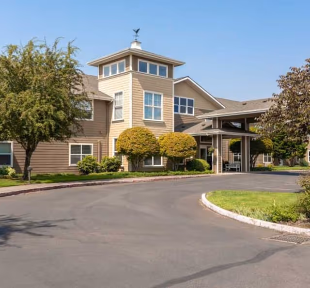 Heron Pointe Senior Living exterior with driveway, landscaping, and covered entrance.