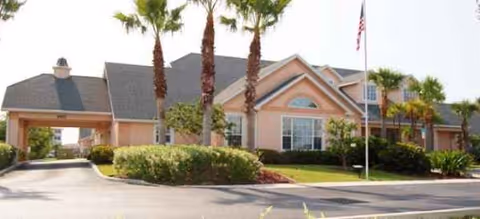 Exterior view of a Brookdale Punta Gorda Isles building with palm trees and flag.