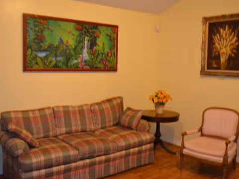Cozy living room with plaid sofa, armchair, side table, and colorful wall art.