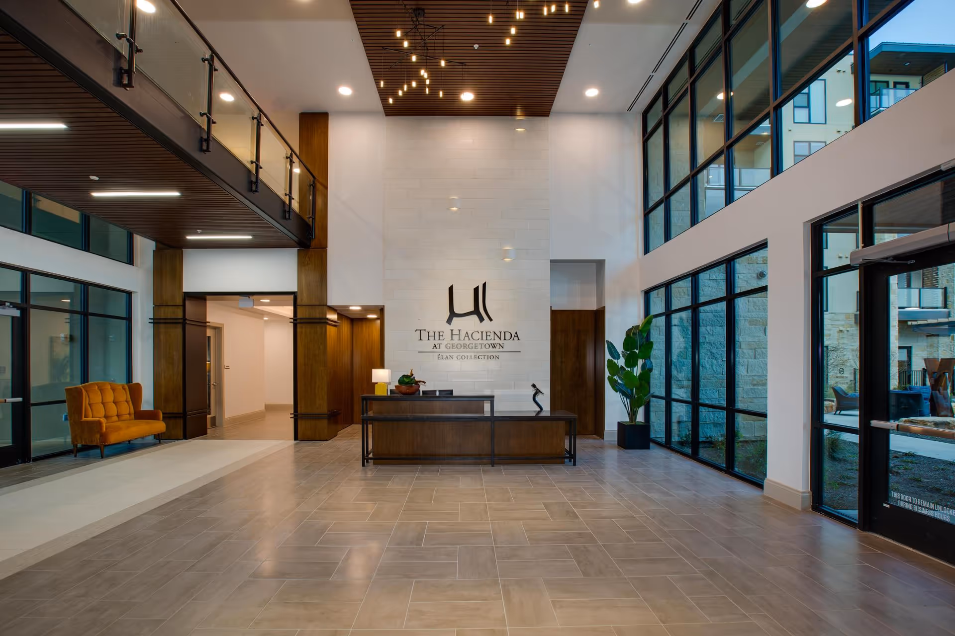 Spacious modern lobby of The Hacienda at Georgetown with a central reception desk, high ceilings, large windows, and seating.