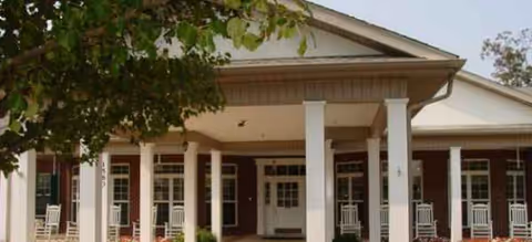 Exterior view of a senior living facility with a covered porch and white columns.