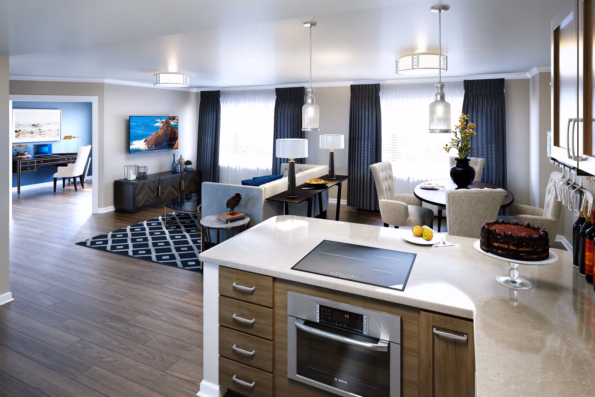 Open-plan interior showing a modern kitchen island with stovetop and cake in the foreground and a living and dining area with sofa, TV, and table in the background.