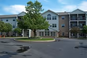 Two-story Anderson Farms Apartments building with brick siding, curved driveway, trees, and a parking lot.