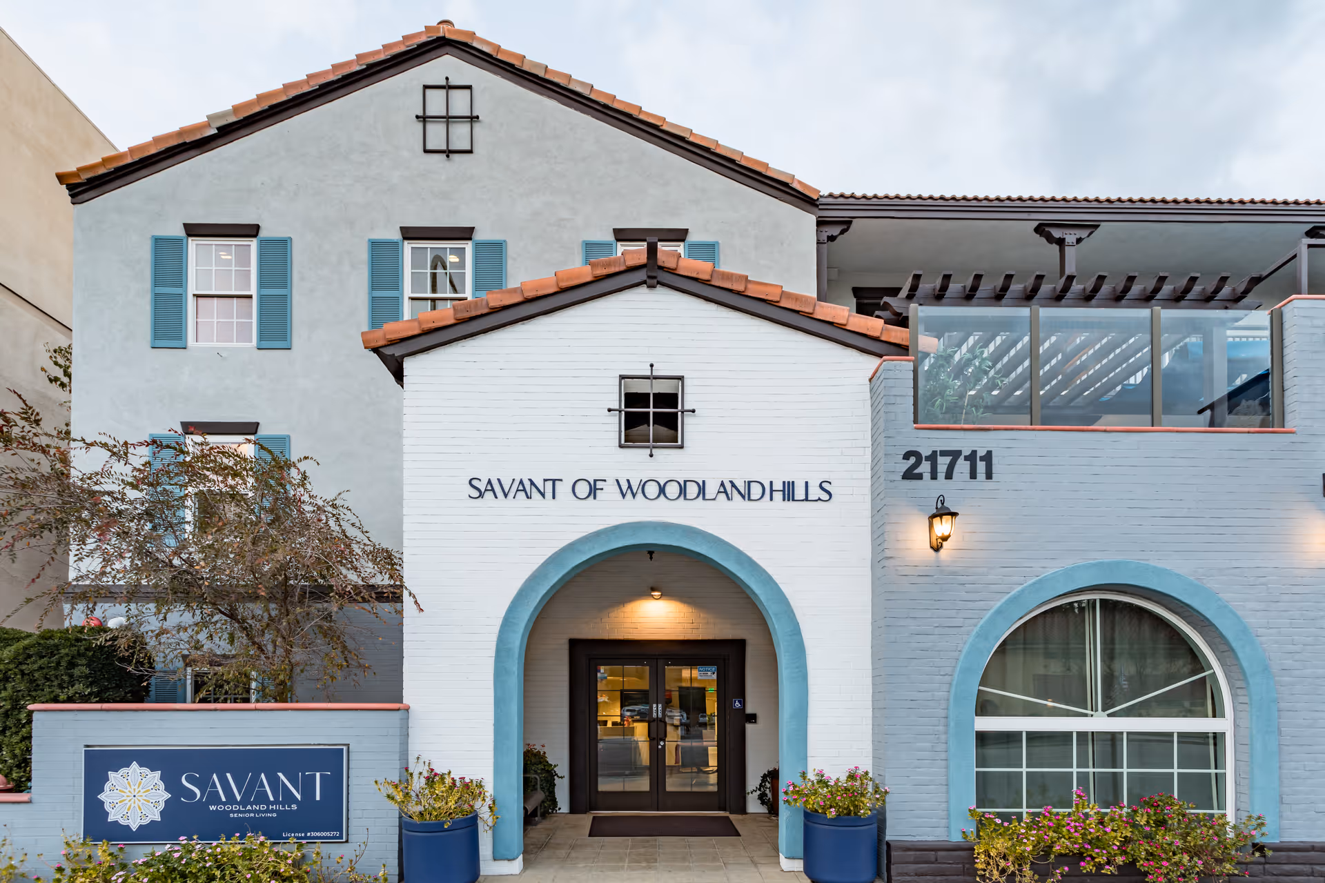 Front exterior entrance of the Savant of Woodland Hills building with an arched doorway and address number 21711.