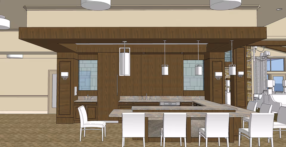Interior rendering of a modern kitchen area with a large island countertop surrounded by white chairs. The kitchen features wood cabinetry, pendant lighting, and a tiled backsplash. Adjacent dining area with additional seating is visible in the background.