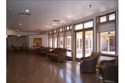 Spacious common area with wicker chairs and sofas lined along large windows overlooking an interior courtyard.