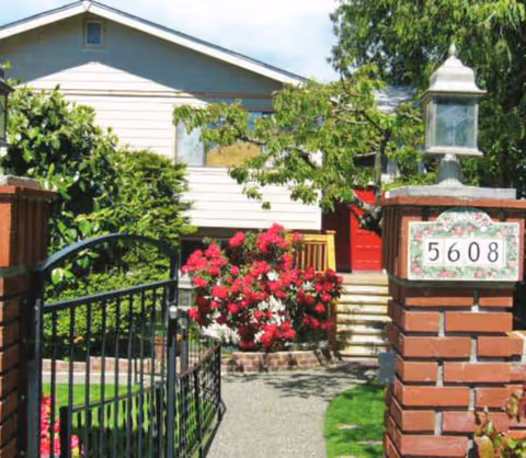 Front entrance of a home with a brick gate pillar, path, and blooming roses