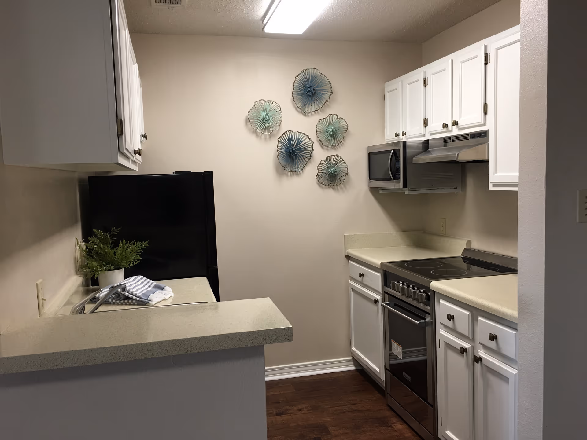 Compact kitchen in a Williamsburg Senior Living unit with white cabinets and stainless appliances.