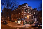 Brick University Center exterior at night with illuminated windows and parked cars along a street corner.