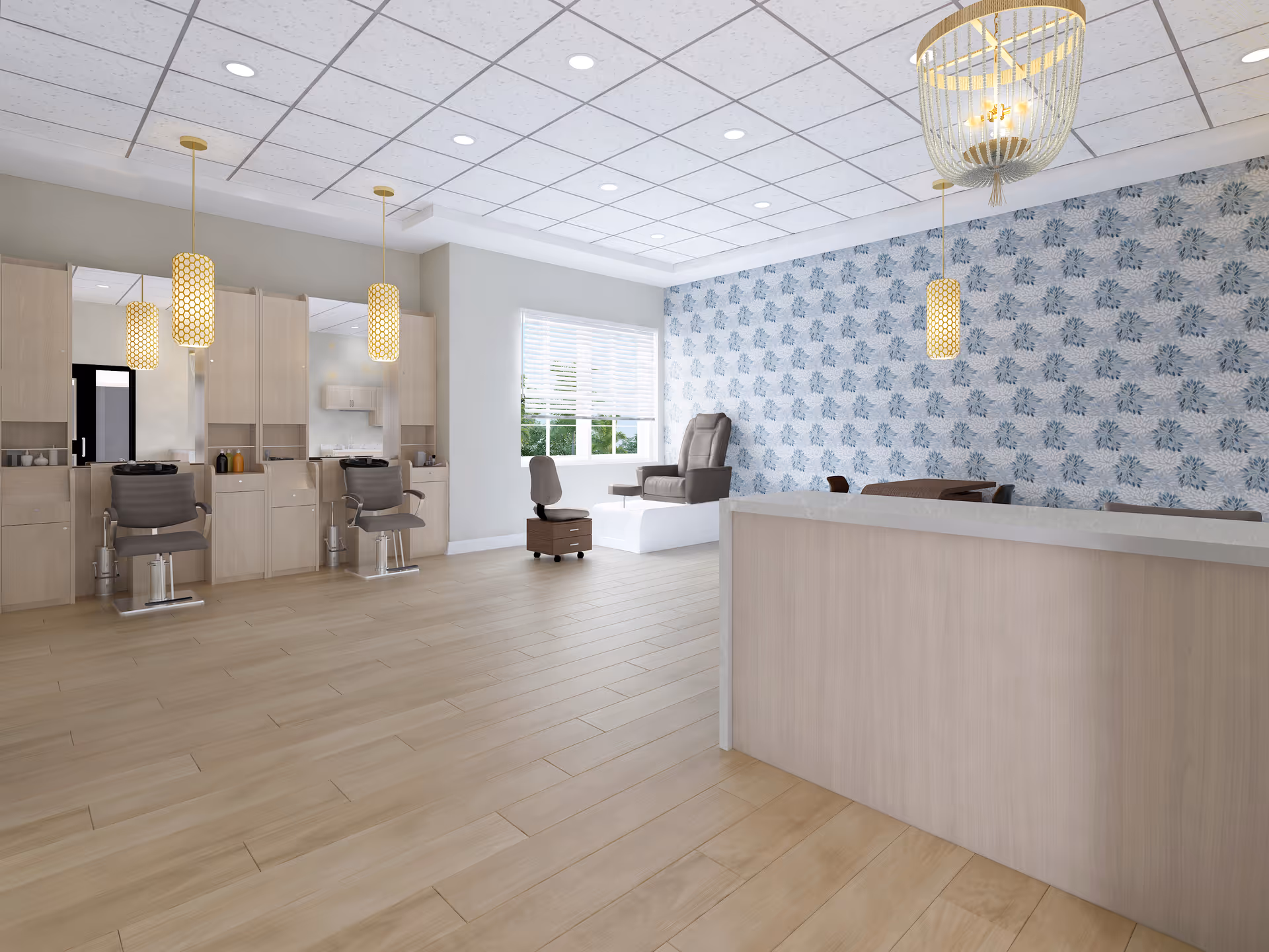 Interior view of a salon area in a senior living facility with light wood flooring, three salon chairs in front of mirrors and cabinets, a reception desk, a comfortable chair near a window with blinds, and pendant lights hanging from a tiled ceiling. The wall behind the reception desk has blue floral wallpaper.