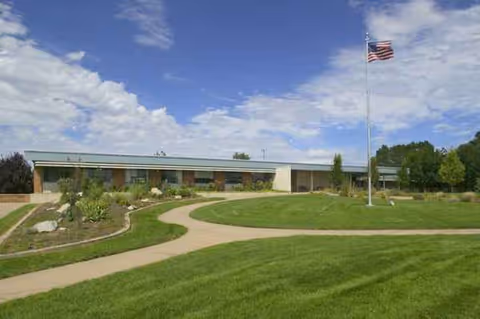Exterior view of Heritage Park Healthcare and Rehabilitation with landscaped lawn and flagpole.