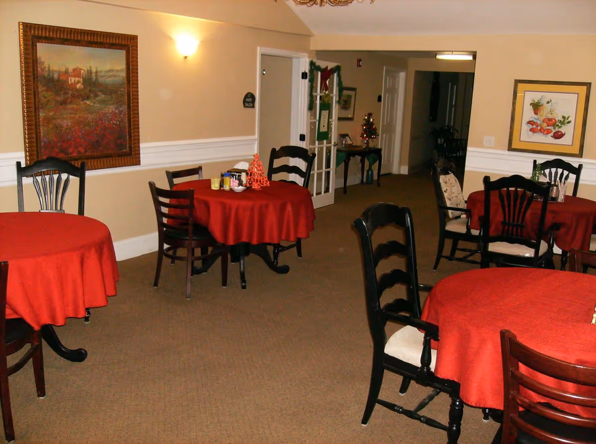 Interior dining area with round tables draped in red tablecloths and wooden chairs.