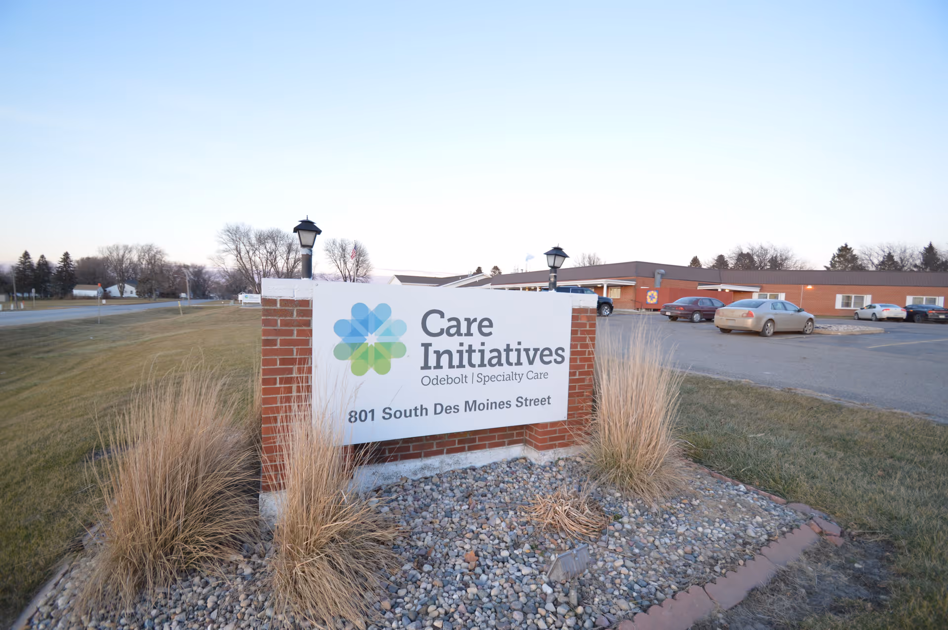 Brick monument sign for Care Initiatives Odebolt Specialty Care at 801 South Des Moines Street in front of a low brick building and parking lot.