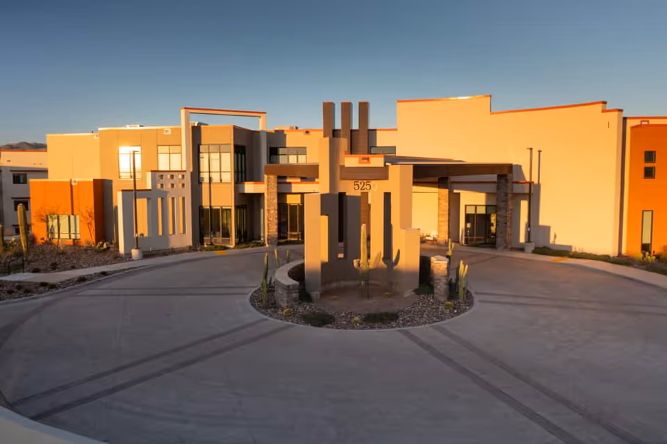 Front exterior of a modern building with a circular driveway and a central cactus planter displaying the number 525.