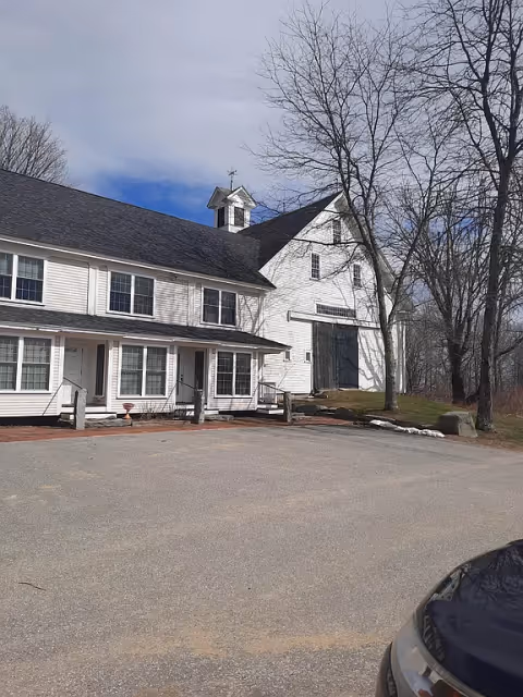 Exterior view of Canterbury Hall, a white building with parking lot and leafless trees.