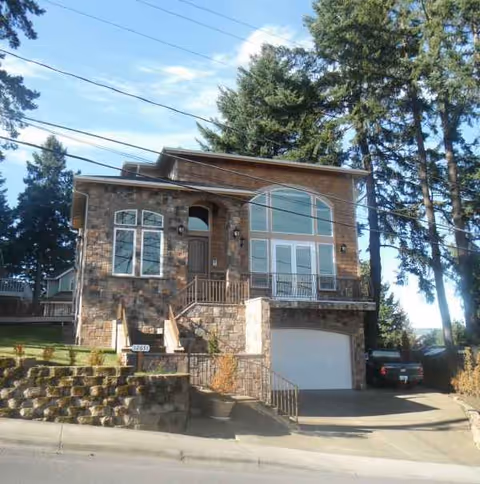 Two-story brick-and-stone residence with large arched windows and a front driveway.