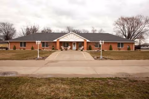 Single-story brick senior living facility exterior with a central entrance and curved driveway.