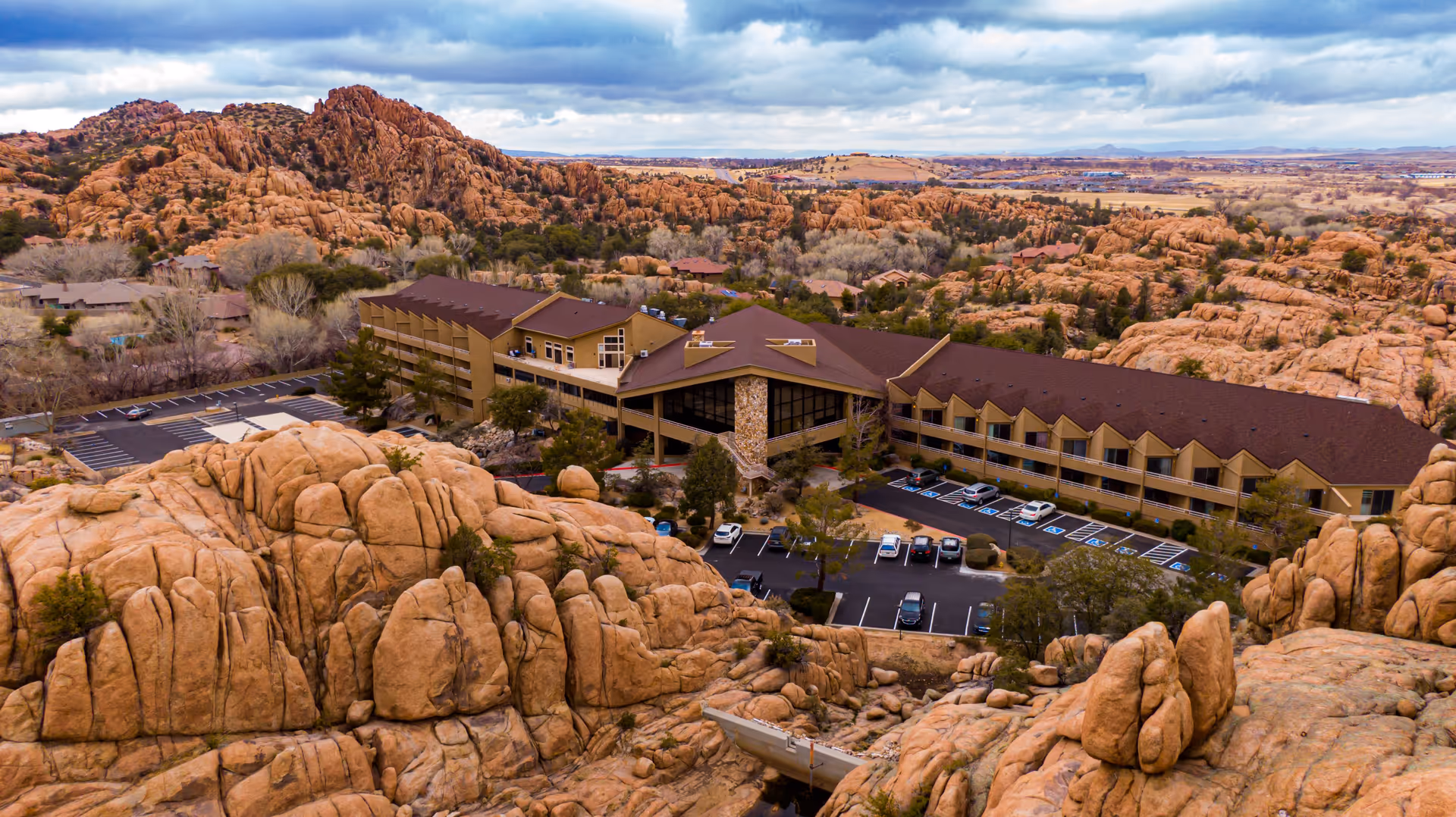 Aerial view of a senior living facility building nestled among large rocky outcrops and desert landscape.