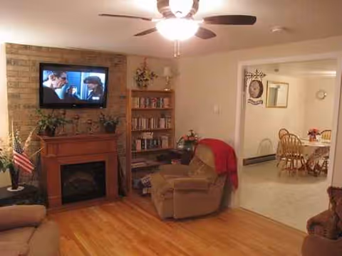 Cozy living room in a senior facility with fireplace, TV, and seating.