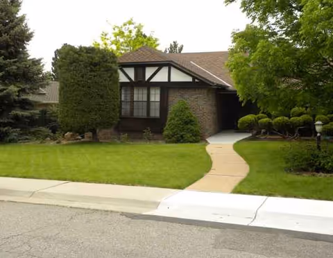 A single-story brick senior living facility with a manicured lawn and walkway