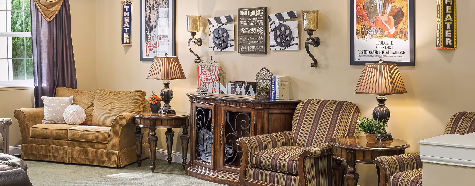 Cozy living room with a sofa, striped armchairs, side tables and lamps, and movie-themed wall decor.