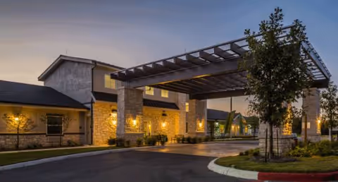 Exterior view of The Legacy at Forest Ridge entrance with stone columns and illuminated canopy.