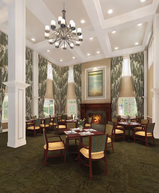 A spacious dining room with multiple wooden tables and chairs arranged neatly. The room features tall windows with green patterned curtains, a large chandelier hanging from a high ceiling with recessed lighting, and a fireplace with a framed painting above it. The carpet is dark green, complementing the overall elegant and cozy atmosphere.