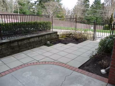 Outdoor tiled patio with black railing and raised garden beds beside it.