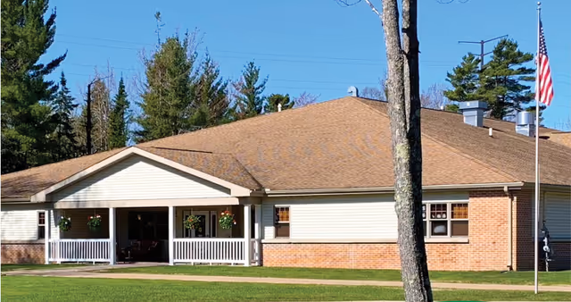 Front view of a single-story assisted living building with a porch and American flag.