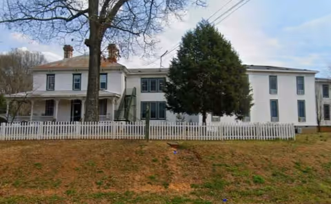 Front exterior of Burnt Hickory Residences: a white two-story building behind a white picket fence.