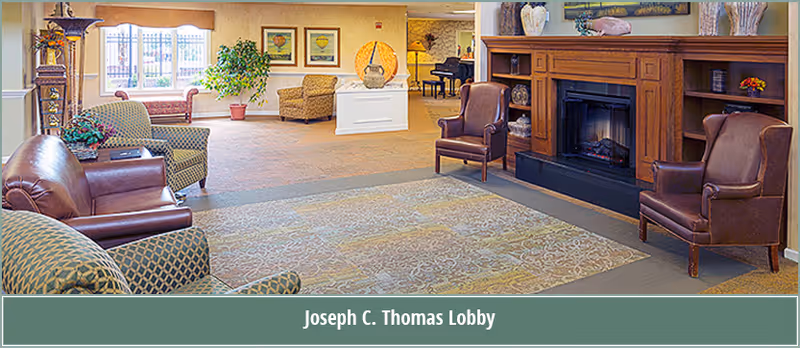 Spacious senior living lobby with multiple chairs, a fireplace, and decorative furnishings.