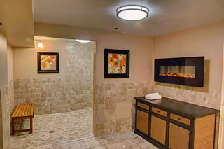 A tiled interior room with bench seating, framed art, and a cabinet area.