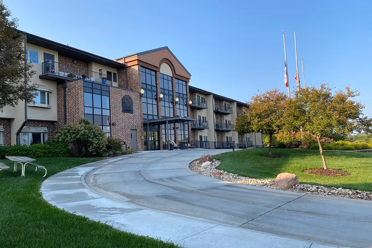 Exterior view of Chapters Living of Council Bluffs with a brick entrance, curved driveway, and landscaped lawn.