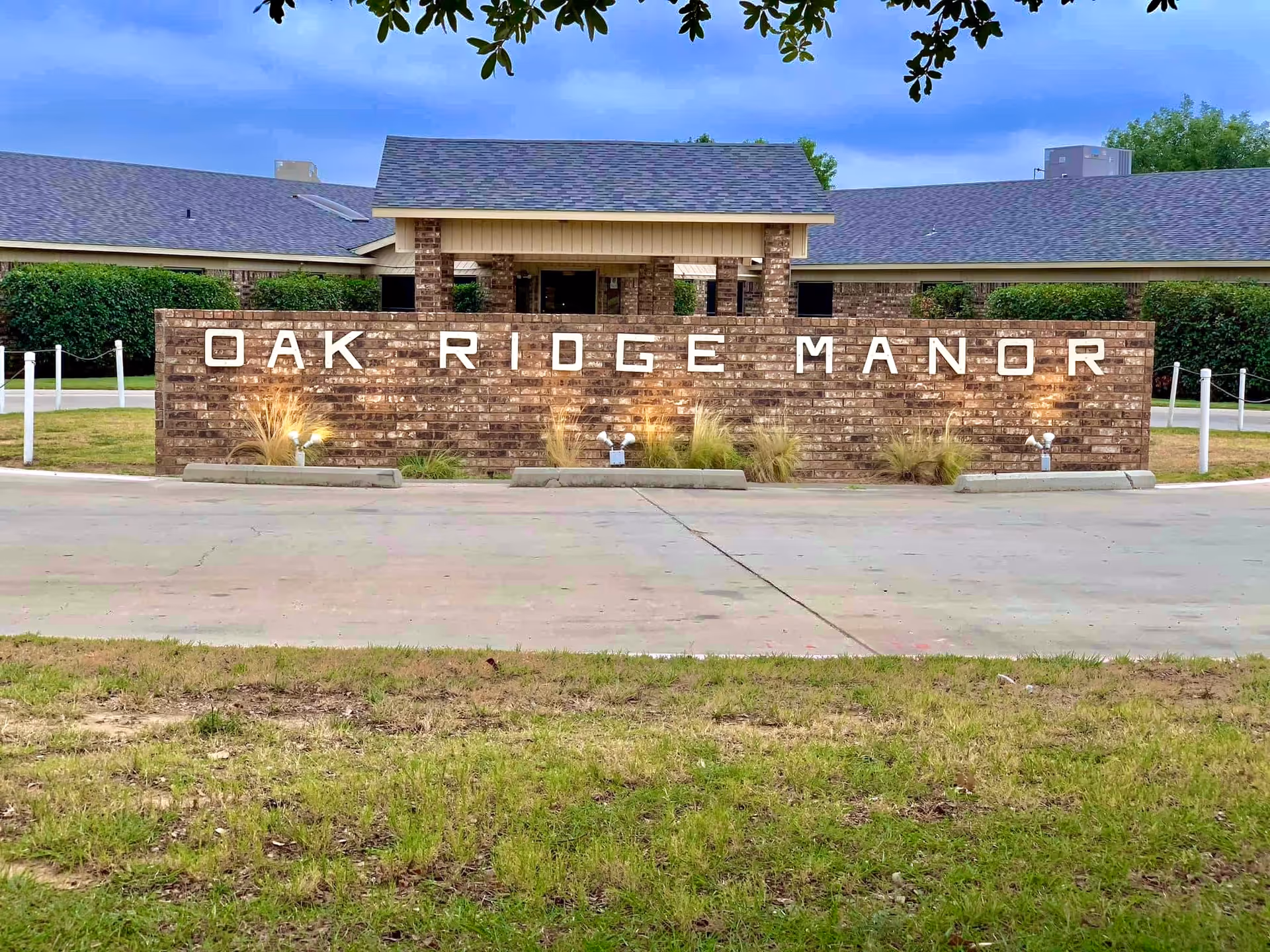 Brick entrance sign reading "Oak Ridge Manor" in front of a single-story nursing facility building.