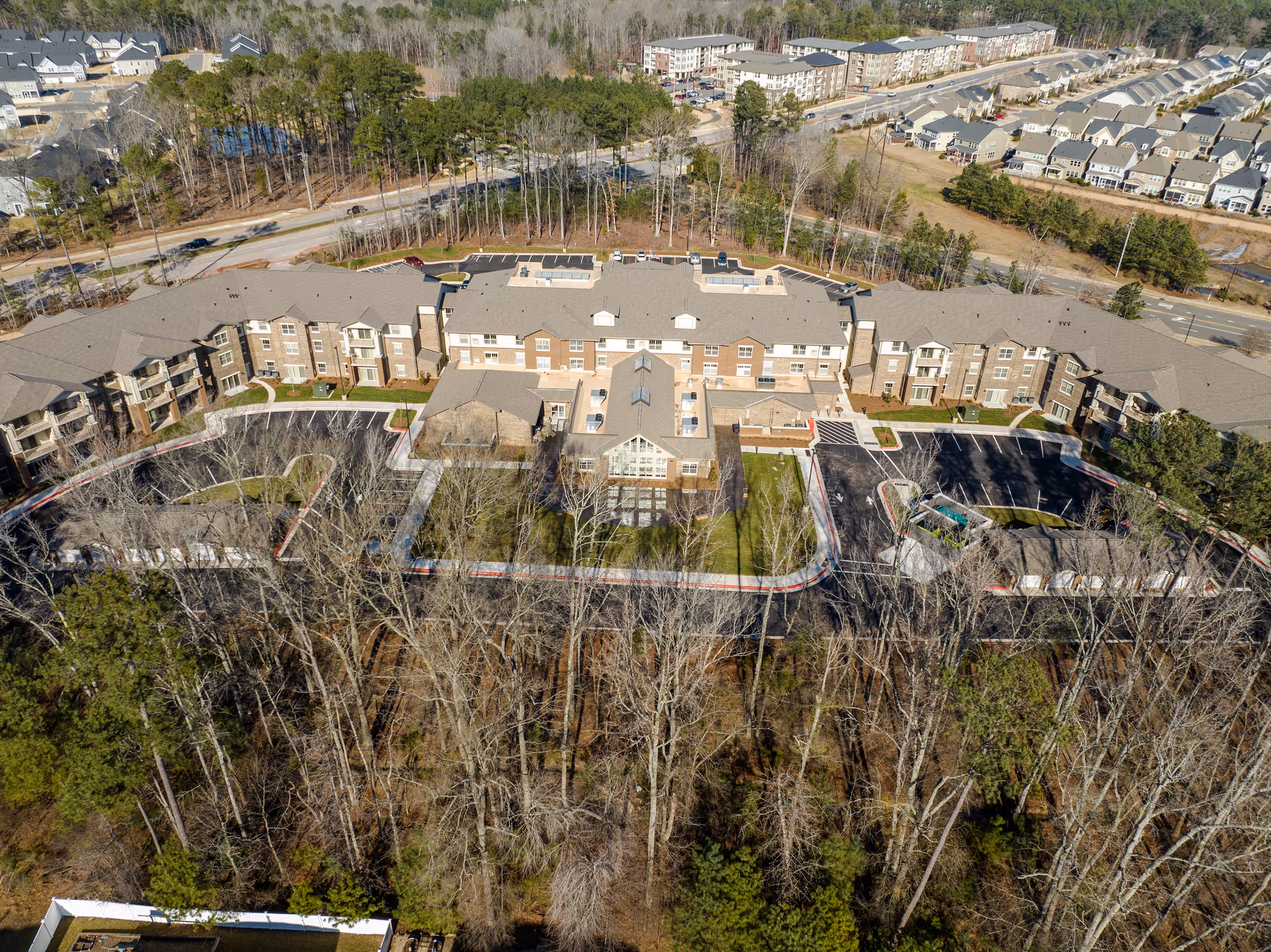 Aerial view of the Brier Pointe Retirement Community building complex surrounded by trees, parking areas, and nearby roads.