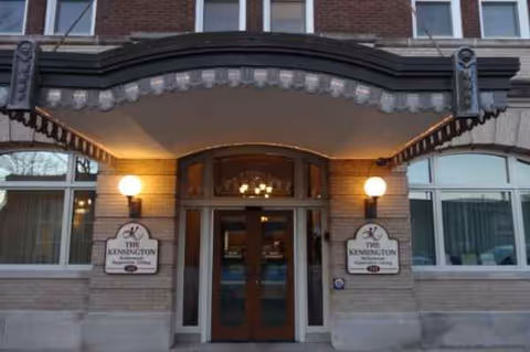Exterior entrance of The Kensington senior living facility with brick facade and arched canopy.