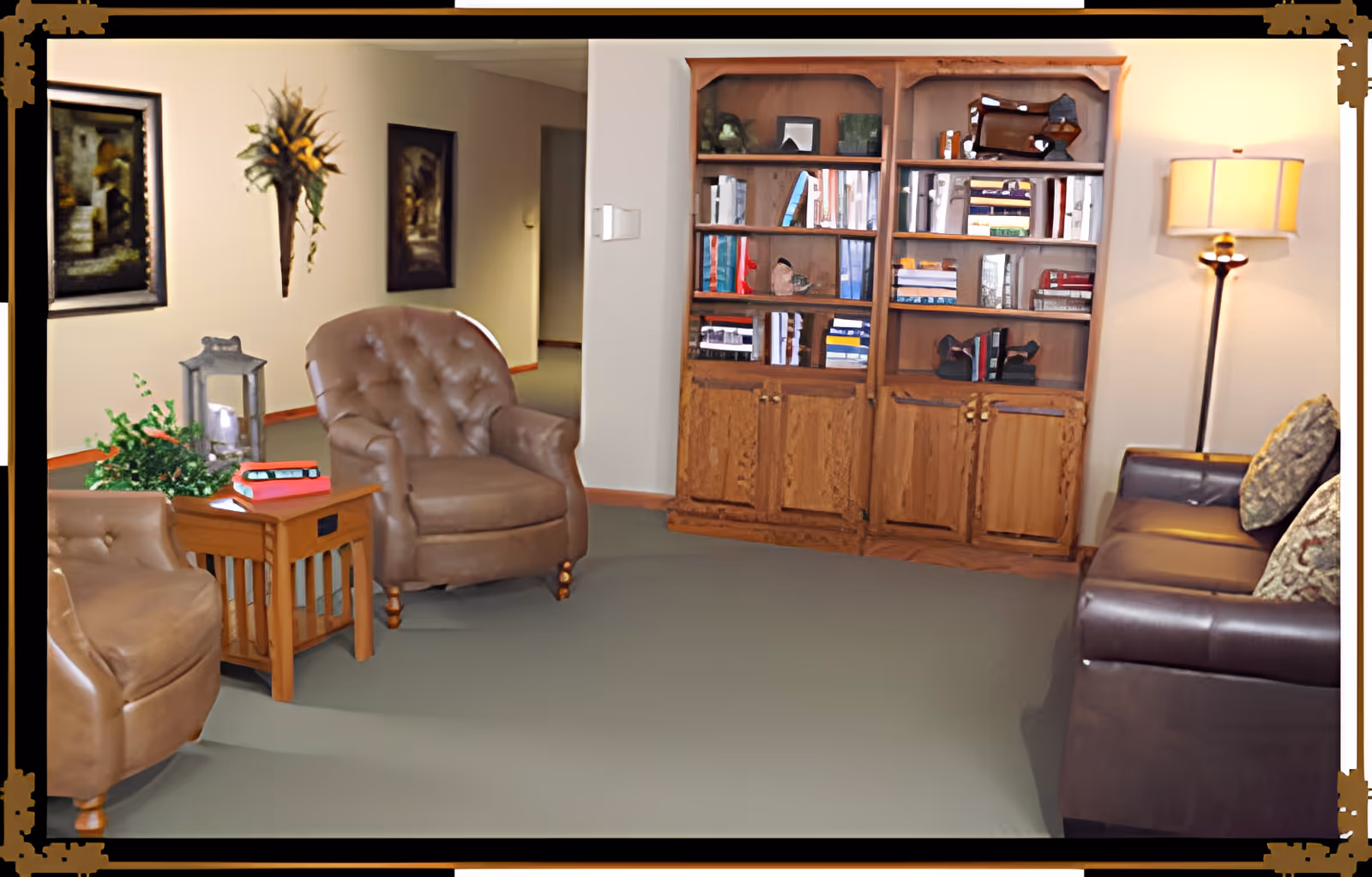 Cozy common room with leather chairs, a wooden bookshelf, side table and a floor lamp.