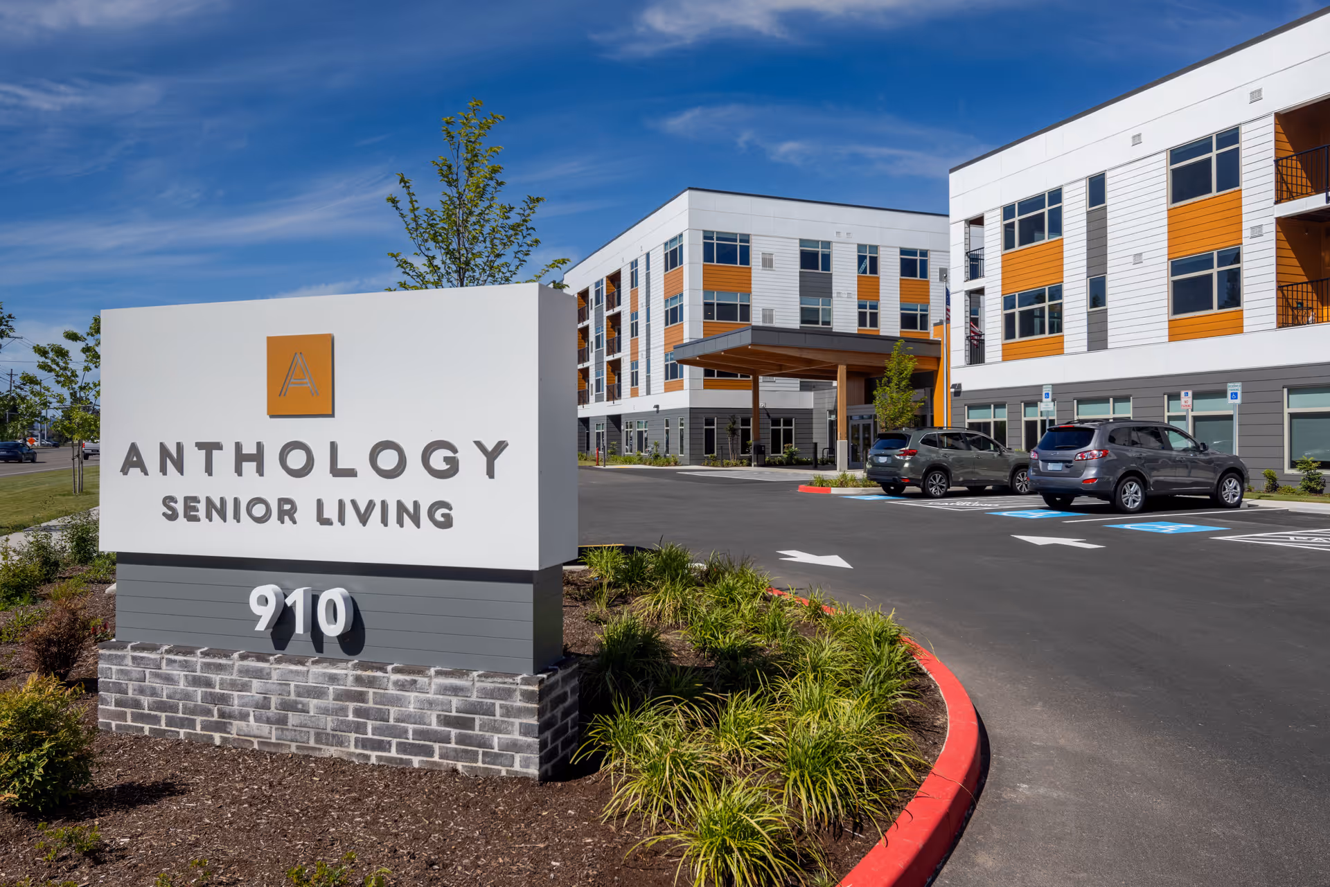 Exterior view of a modern senior living facility with a large sign and parking.
